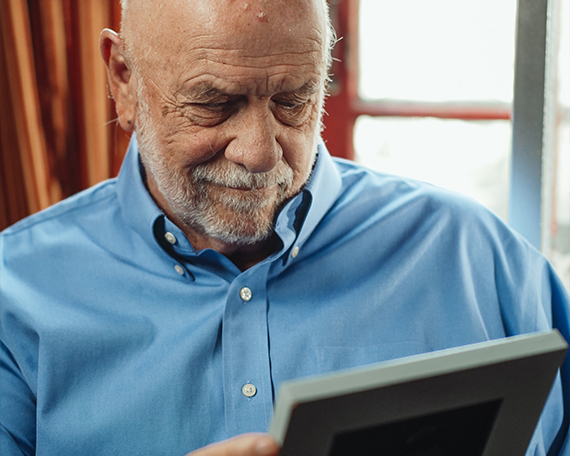 elderly man looking at a framed photo fondly