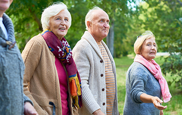 4 elderly residents on a walk together outside smiling in the distance