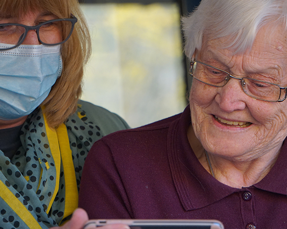 resident and nurse looking at a phone