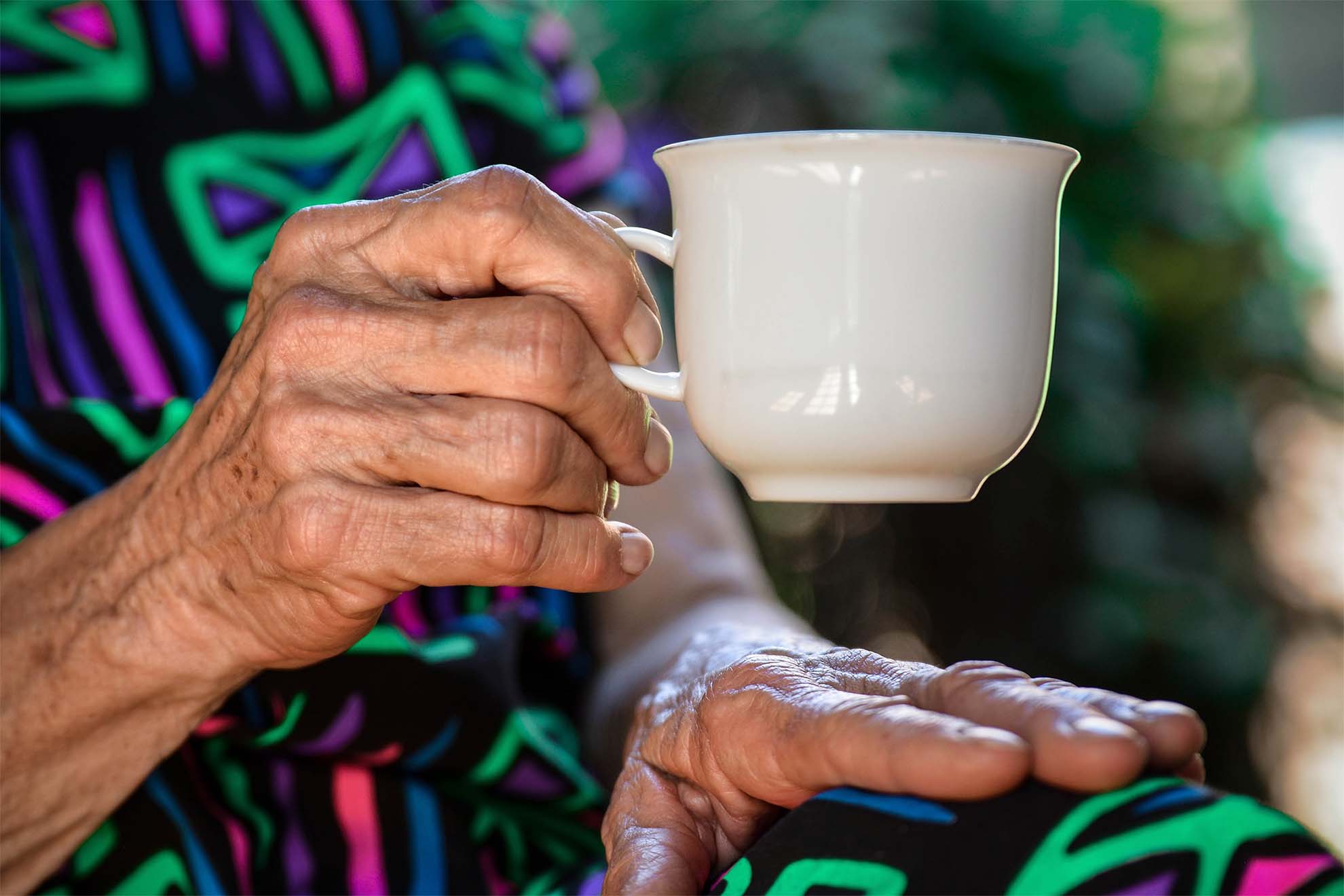 close up of white mug in elderly woman's hand