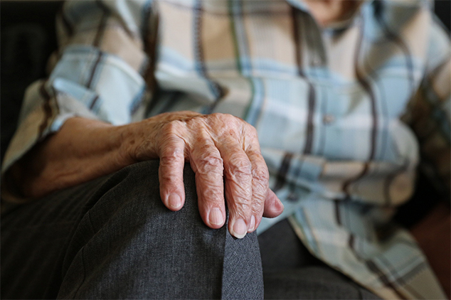 close up of elderly man with his hand on his knee
