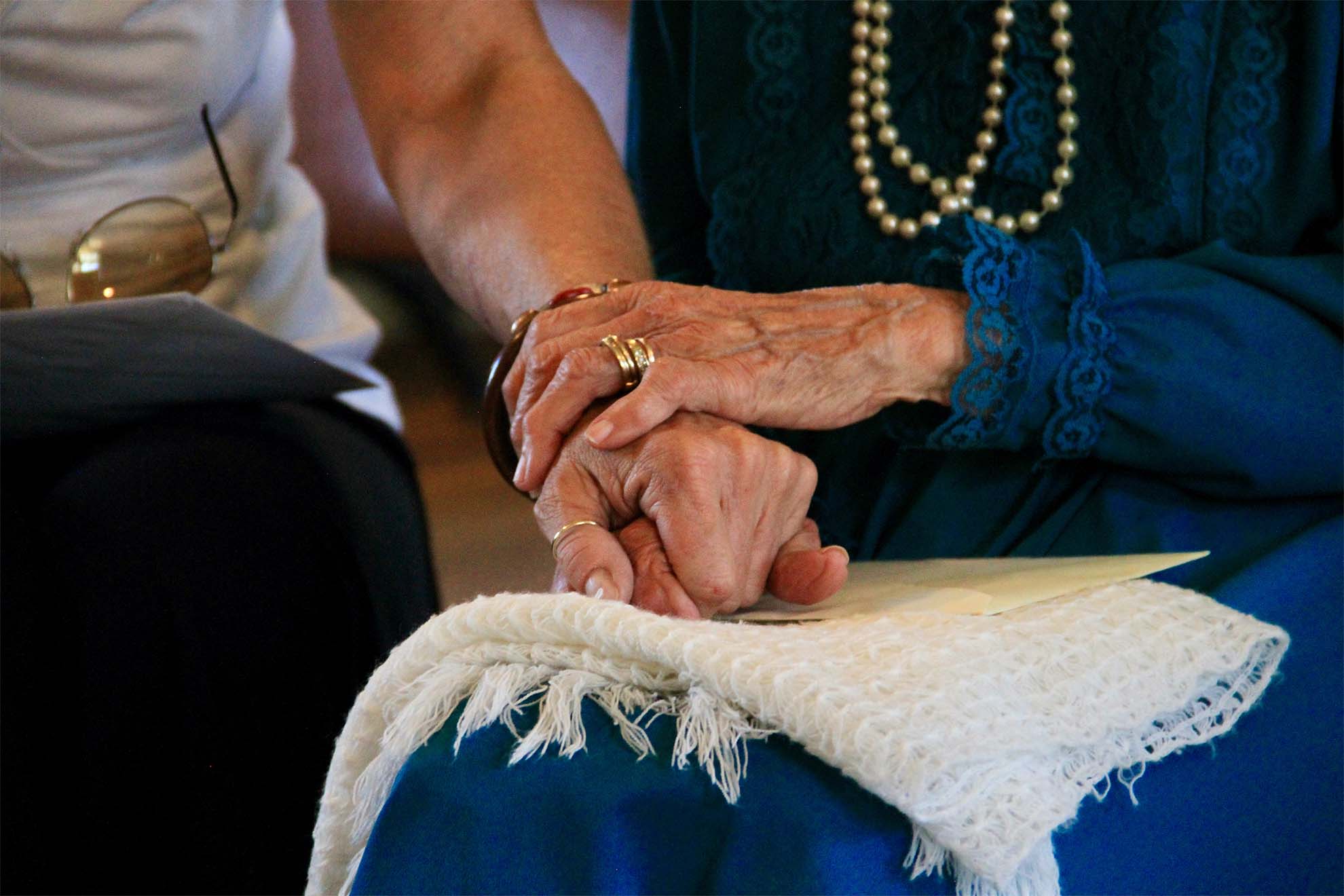 2 elderly residents sat down together holding hands