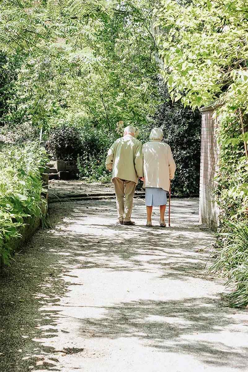 two residents walking down a woodland path holding each other