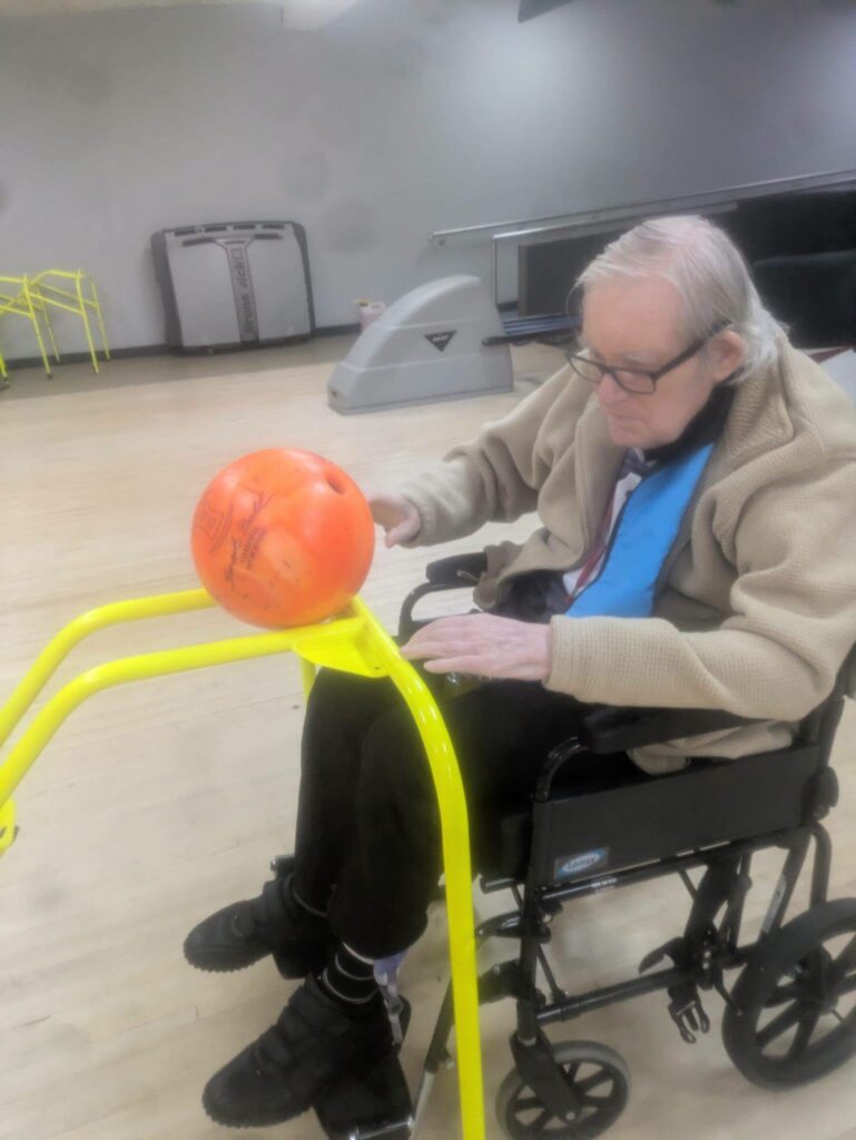 older man sat in a wheelchair with a bowling ball