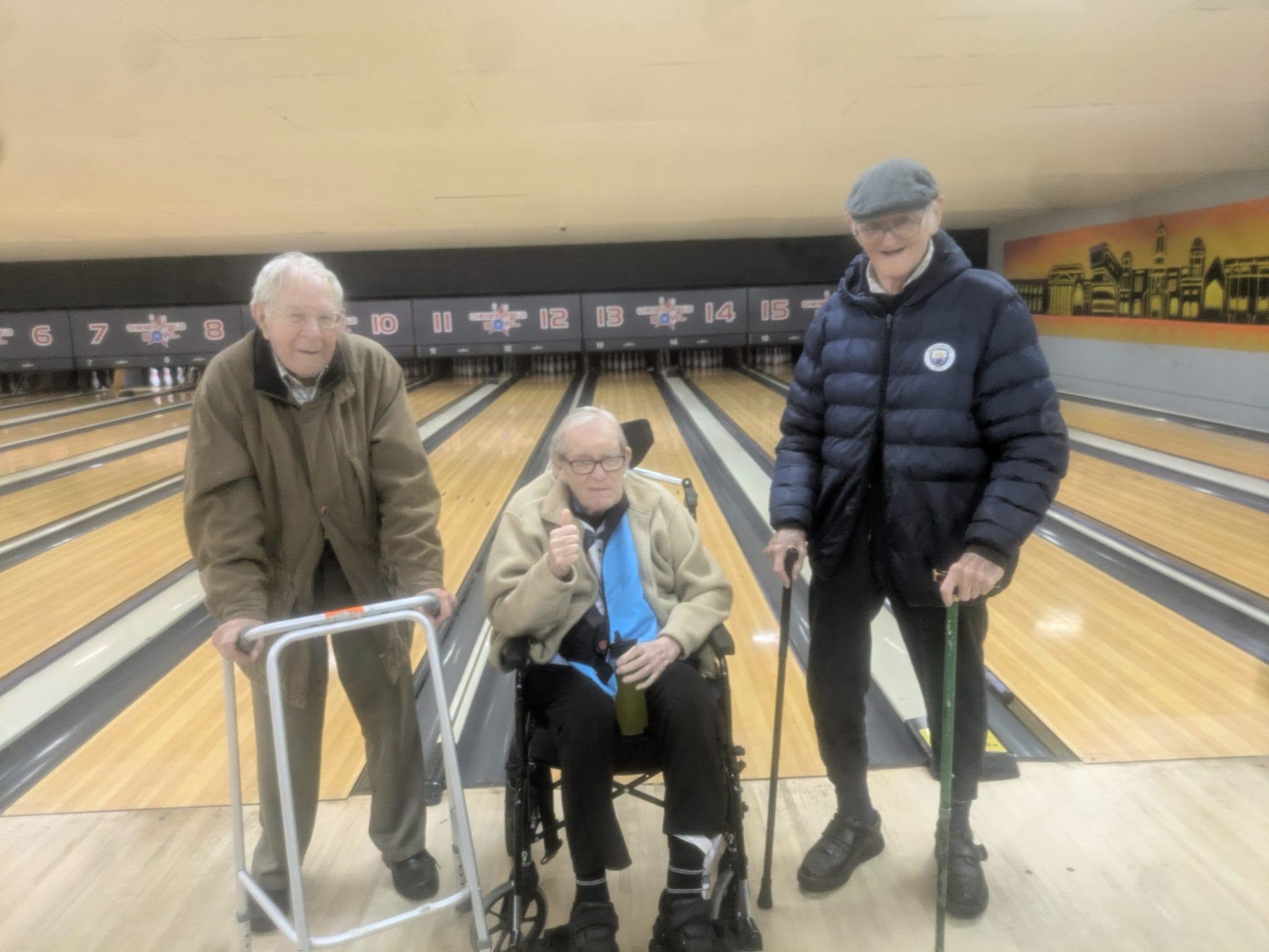 three older men standing at a bowling alley